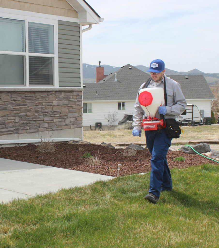 A Prompt Pest Solutions technician spreading granular pest control treatment on a lawn in Pocatello, ID.