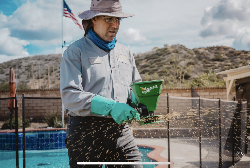 A Critter Gitters technician spreading pest control granules near a swimming pool in Lakeside, CA.