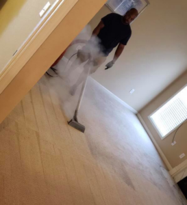 A technician steam cleaning a carpet in a residential room, provided by Harper's Carpet & Upholstery Cleaning in San Antonio, FL.