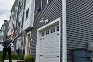 A Bye Bye Pest Solutions technician using a long pole to treat the eaves of a house for pest control in Hanover, PA.