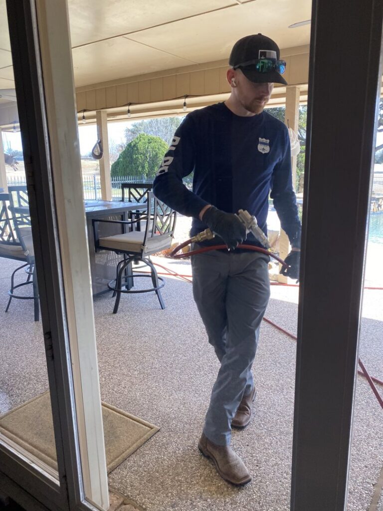 A Blue Line Pest Police technician treating the patio door area for pest control in Fort Worth, TX.