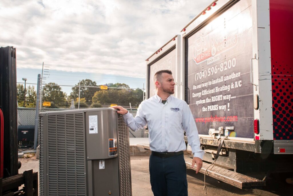 A technician unloading a new outdoor HVAC unit from a company truck at Parks Heating Cooling Plumbing & Electrical in Indian Trail, NC