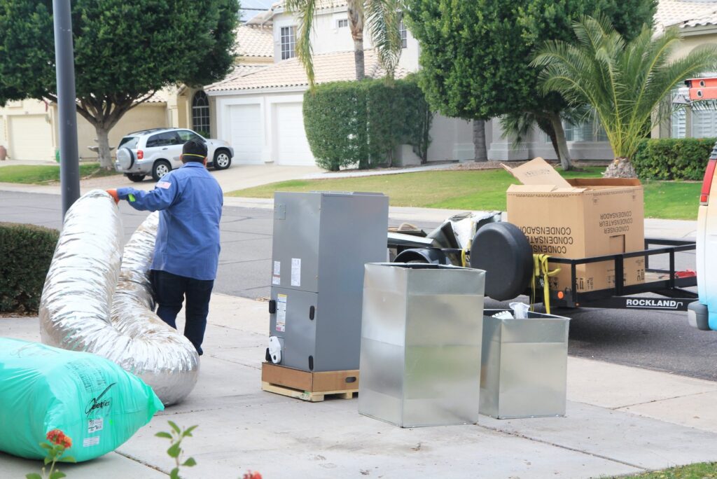 A technician unloading new HVAC equipment and ductwork from a trailer for A/C Valley, LLC in Tempe, AZ.
