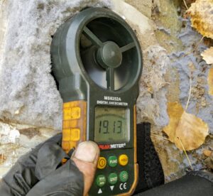 A technician using a digital anemometer to measure airflow during a chimney inspection by Chimney Karma in Fort Collins, CO.