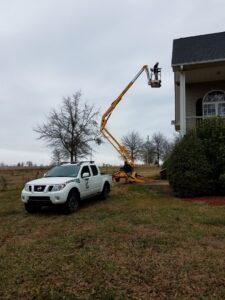 A technician using a boom lift to access a high area of a house for pest control services by Athens Exterminating Inc. in Athens, GA