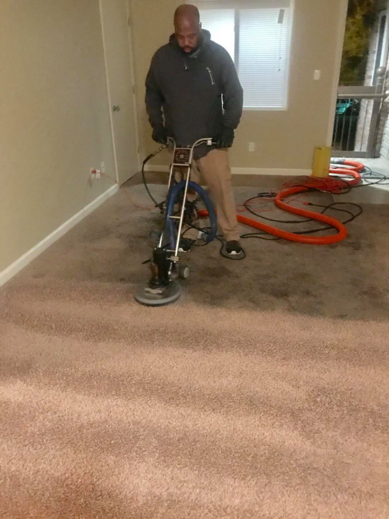 A technician operating a rotary carpet cleaning machine to deep clean a carpet for Harper's Carpet & Upholstery Cleaning in San Antonio, FL.