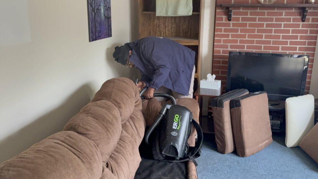 A SanPro Pest Control VA technician vacuuming furniture during a pest control service in Richmond, VA.