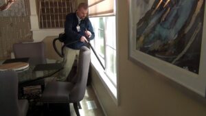A technician vacuuming inside a home for pest control services by Springer Professional Home Services in Des Moines, IA.