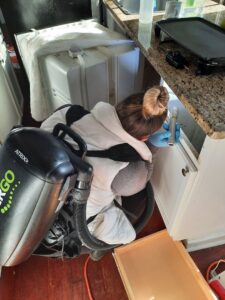 A technician using a backpack vacuum to clean under a kitchen cabinet, part of pest control cleanup by Direct Pest Solutions Of Georgia, LLC in McDonough, GA.