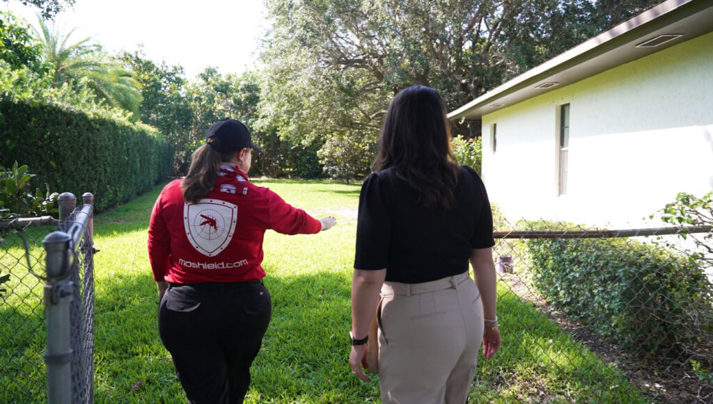 A Mosquito Shield technician walking through a backyard with a client in North Attleboro, MA, for a pest control assessment.