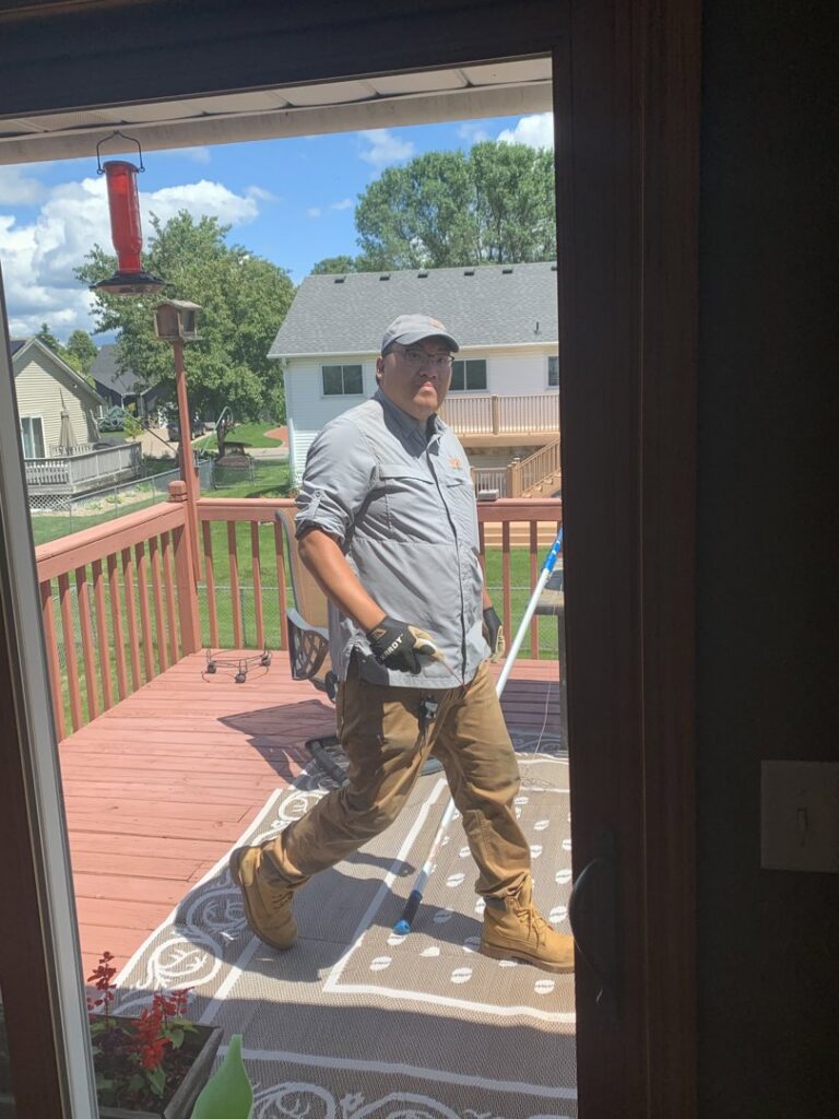 A pest control technician walking onto a residential deck after completing a service for Pest Free Rochester in Rochester, MN.