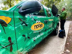 A Noosa Pest Management, LLC technician preparing equipment next to a branded service truck in Columbia, SC.