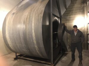 A technician standing next to a large commercial HVAC blower unit, indicating service by Commercial Service in Bloomington, IN.