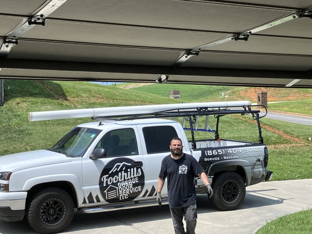 A Foothills Garage Door Service LLC technician standing by the company truck at a job site in Louisville, TN.