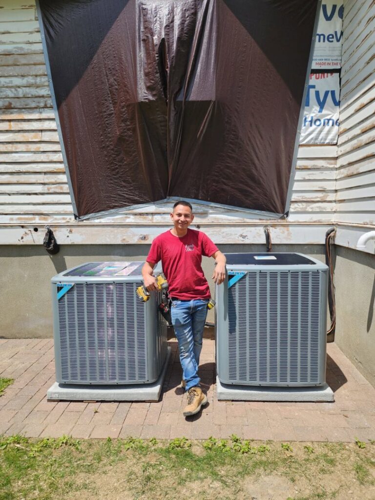 A technician proudly standing next to newly installed Daikin outdoor AC units by Enviromax Heating & Cooling in Peekskill, NY.