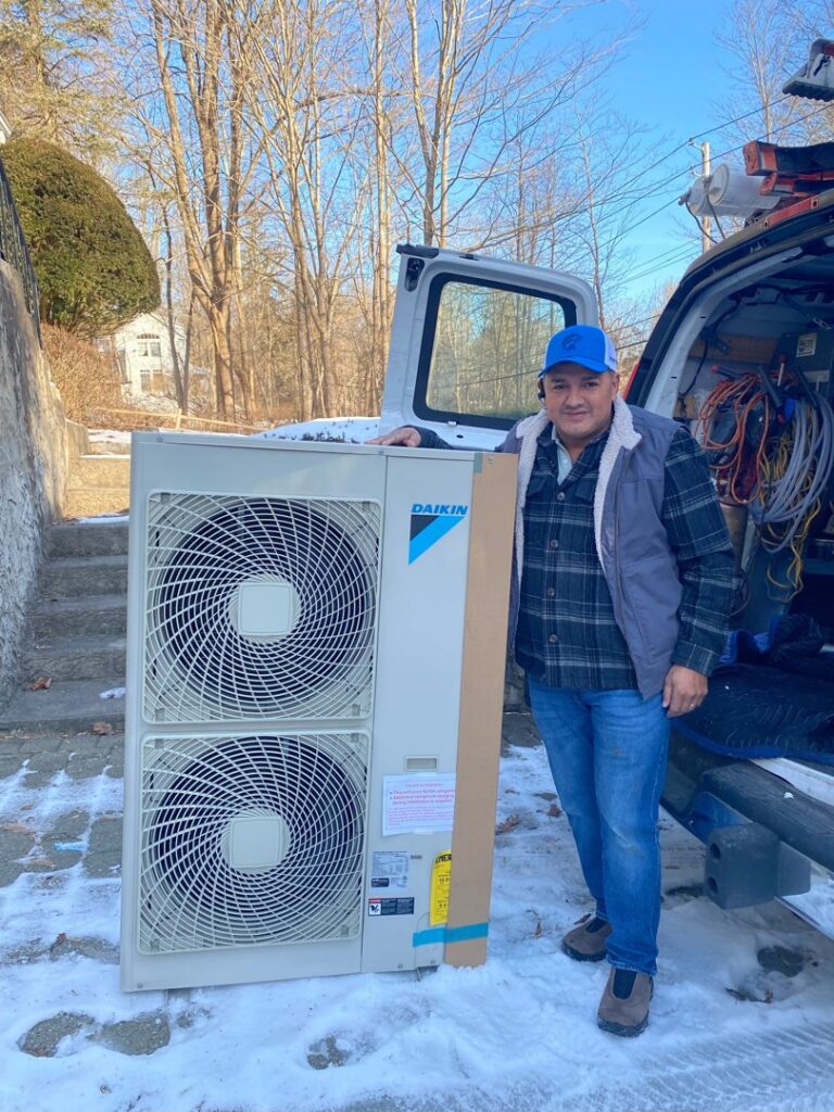 A technician standing next to a newly installed Daikin heat pump unit by Enviromax Heating & Cooling in Peekskill, NY.