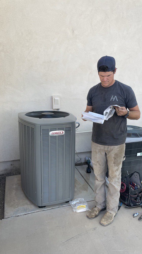 A Hicken Air technician reviewing paperwork next to a new Lennox outdoor HVAC unit installation in Gilbert, AZ