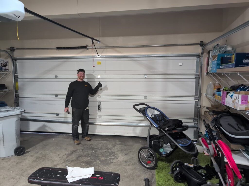 A technician giving a thumbs up next to a newly installed white garage door by AAA Garage Door Services in Renton, WA