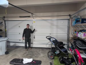 A technician giving a thumbs up next to a newly installed white garage door by AAA Garage Door Services in Renton, WA