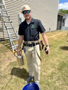 A Sustainable Pest Systems technician with a sprayer and ladder ready for pest control service in Raleigh, NC.