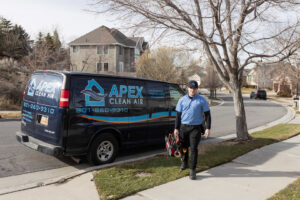An APEX Clean Air technician carrying tools, walking from a service van in South Salt Lake, UT.