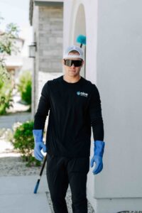 A pest control technician from Aloe Pest Control carrying a web duster for service in Mesa, AZ.