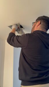 A technician from Kai's Heat & Cool working on a ceiling vent in Naperville, IL