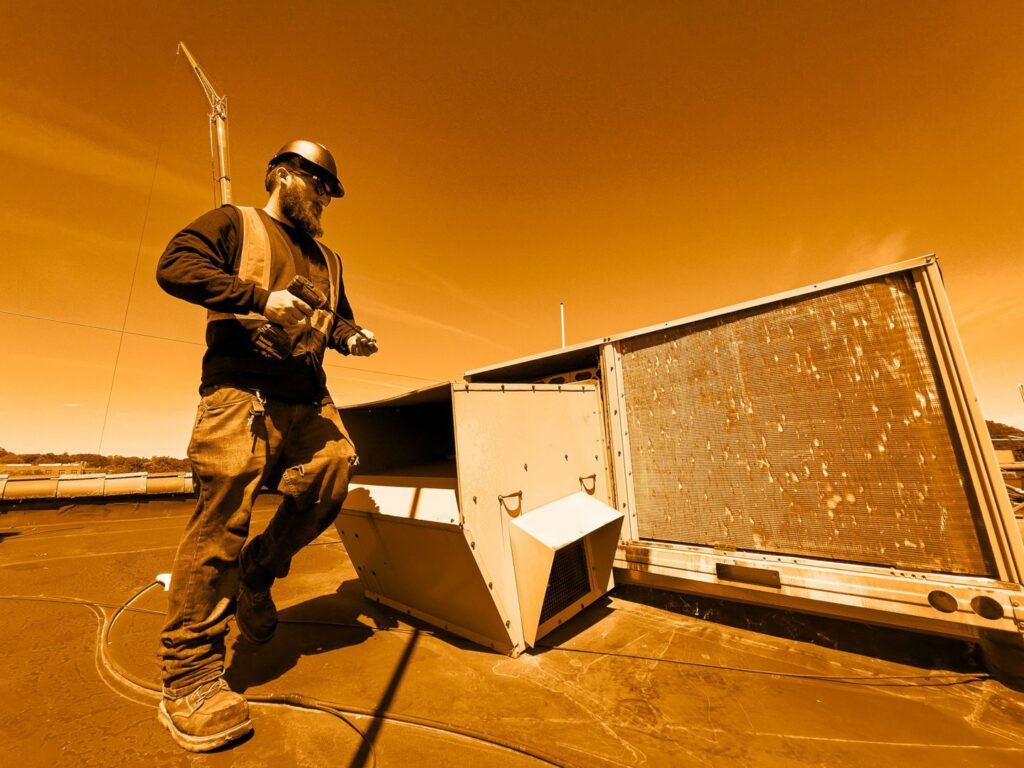 A technician working on a commercial rooftop HVAC unit, demonstrating services by R.J. O'Neil Inc. in Montgomery, IL.
