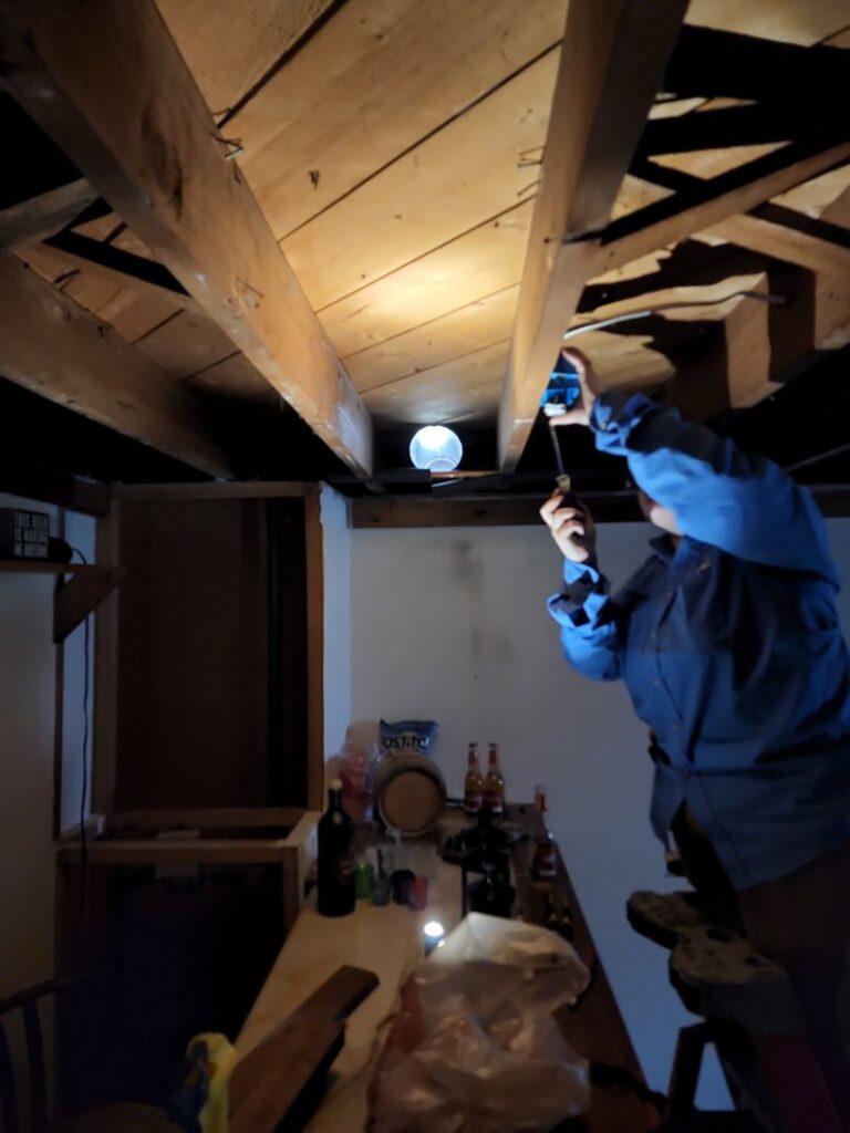 A technician working on ductwork or wiring in an attic or crawl space, performed by Evergreen HVAC Comfort Solutions in Milwaukee, WI.