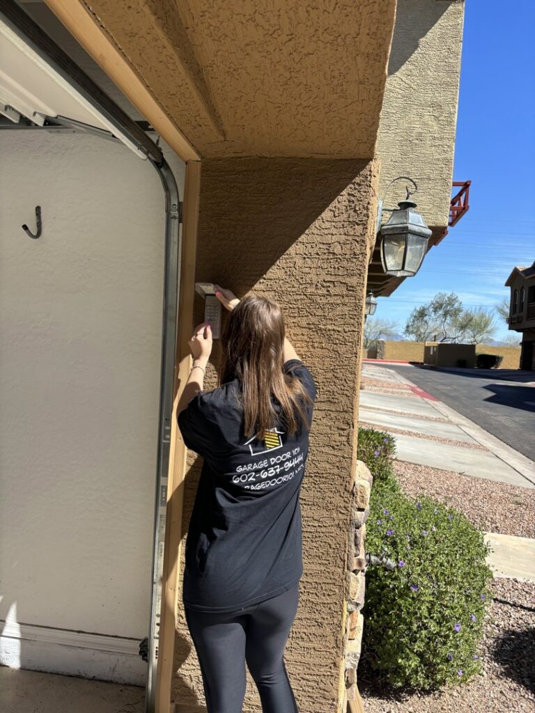 A technician from 101 Garage Doors working on a garage door control panel or frame in Phoenix, AZ.
