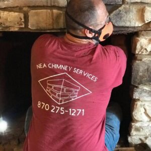 A technician from NEA Chimney Services working inside a fireplace opening in Paragould, AR