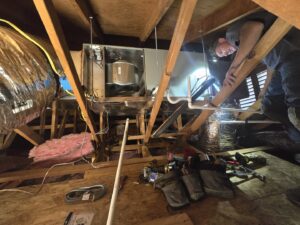 A technician working on an air handler unit in an attic, performing HVAC service for Az AC and Heat Services in Queen Creek, AZ.