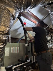 A Community Mechanical technician working on an HVAC system in an attic in Plano, TX.