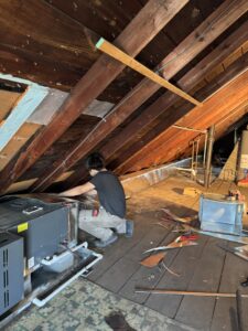 An Hvac Buddies technician working on an indoor HVAC unit in an attic space in Chicago, IL