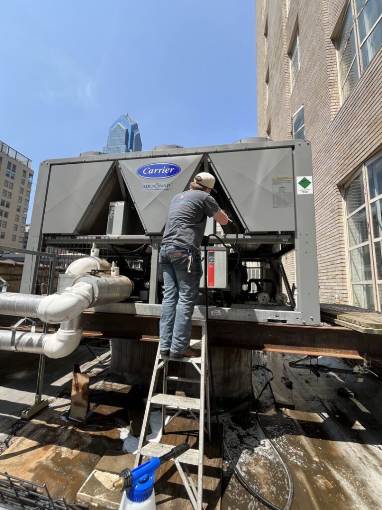 A technician working on a commercial Carrier AquaSnap chiller unit on a rooftop for Green Mechanical LLC in Philadelphia, PA.
