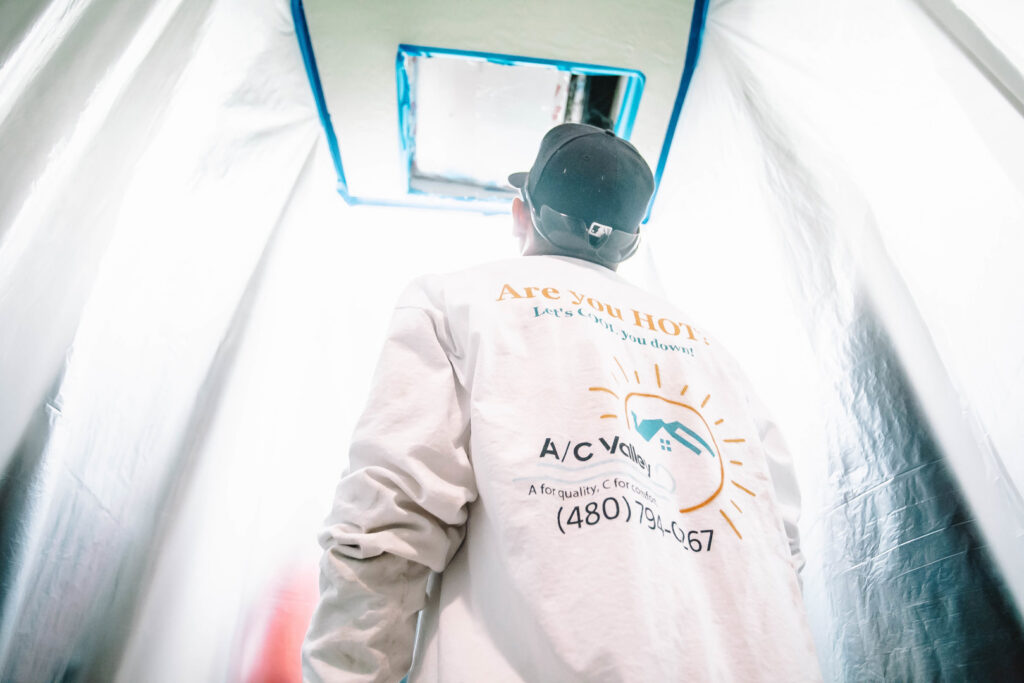 A technician working on ceiling ductwork or a vent, with the area protected, for A/C Valley, LLC in Tempe, AZ.