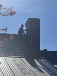 A Soot Masters Chimney Service LLC technician working on a chimney from the rooftop in Jackson, MS.