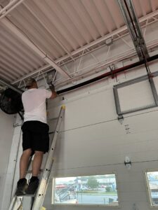 A technician on a ladder working on a commercial garage door system for The Region's Garage Door Repair in Hammond, IN.