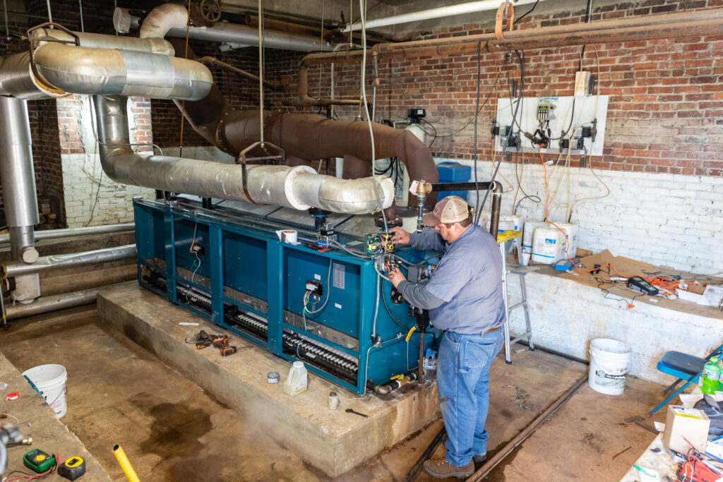 An HVAC technician working on a large commercial heating and cooling system for Comfort Engineering Co Inc in Tupelo, MS