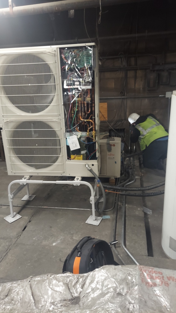 A technician working on a large commercial HVAC unit with exposed components for WC Heating & Cooling Corp. in West Chicago, IL.