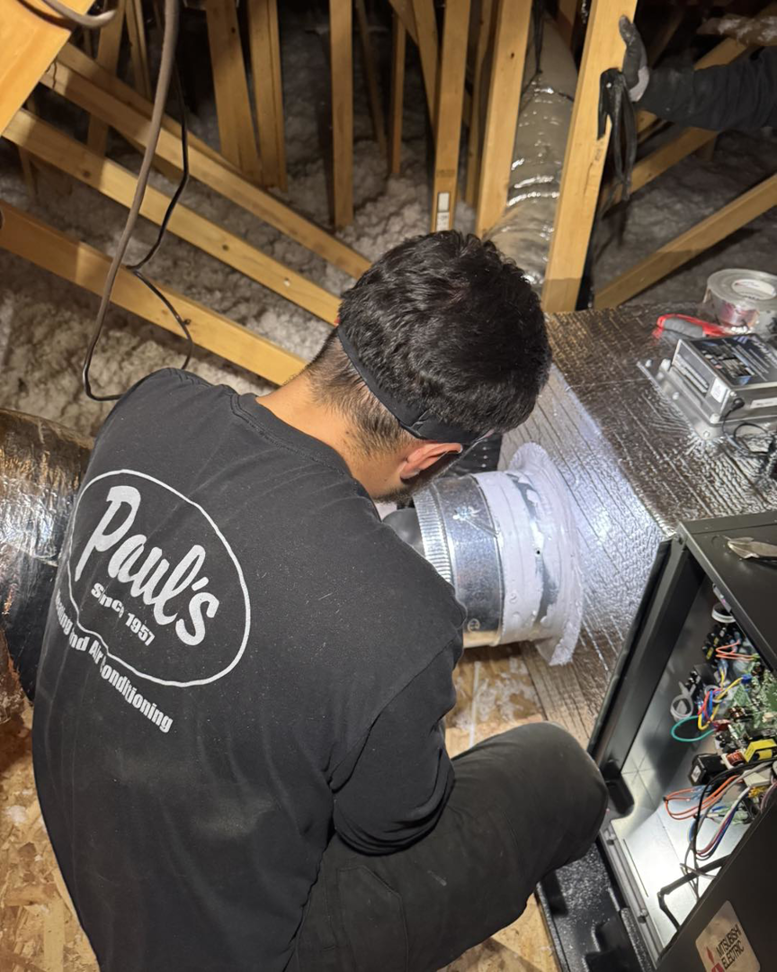 A Paul's Heating & Air Conditioning technician working on ductwork in an attic in Virginia Beach, VA.