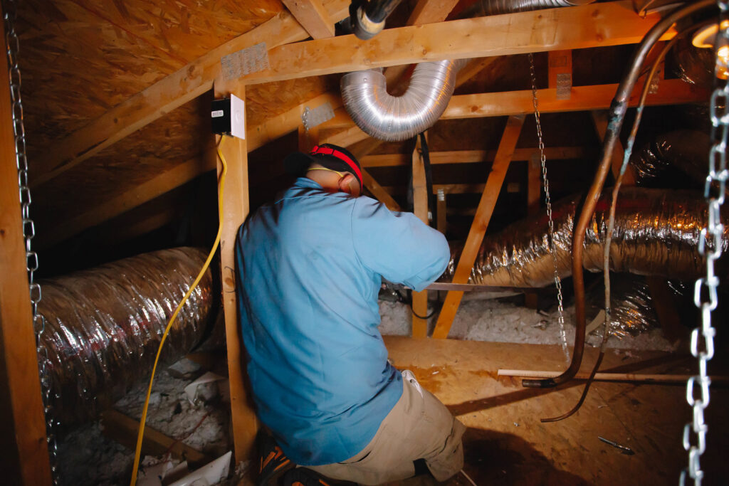 A technician working on ductwork in an attic space for A/C Valley, LLC in Tempe, AZ.