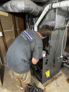 A technician performing maintenance on a furnace at Wickham Heating & Air Conditioning LLC in Rose Hill, KS
