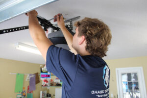 A Chase Door Systems technician working on the overhead mechanism of a garage door in Summerville, SC.