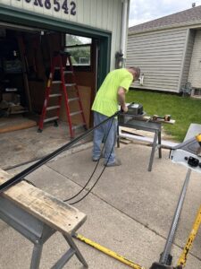 A technician working on a garage door track and opener mechanism outside a garage for Lifetime Door Company in Brookfield, WI.