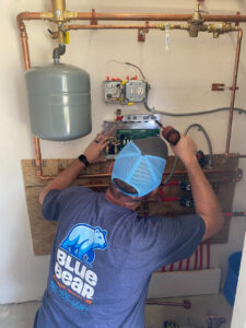 A Blue Bear Plumbing, Heating, & Air technician working on heating system controls in Norwell, MA.
