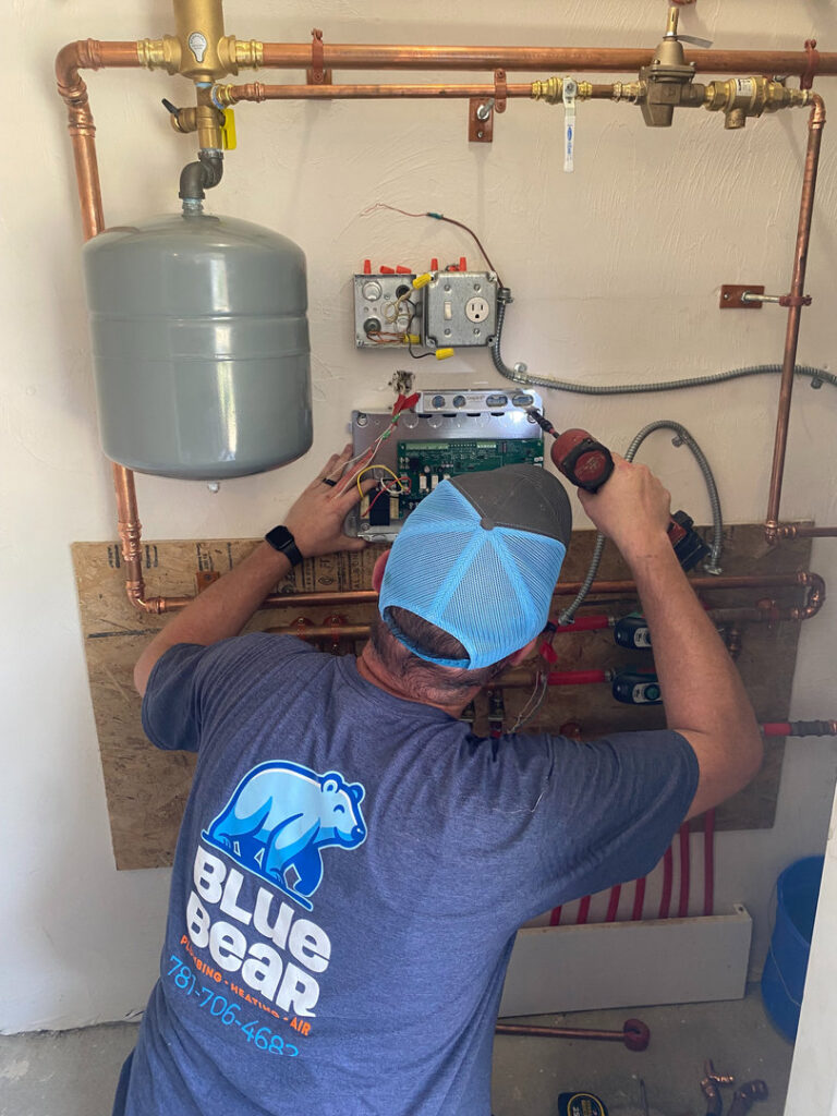 A Blue Bear Plumbing, Heating, & Air technician working on heating system controls in Norwell, MA.