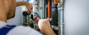 A technician working on a heating system with pipes and valves at Derry Plumbing & Heating in Derry, NH.