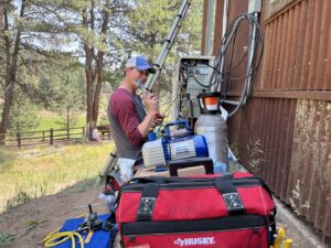 An HVAC technician from Just Heat Pumps works on the electrical connections for a heat pump unit in Denver, CO.