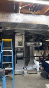 A technician working on an HVAC system installation in a basement for Ultra Installs in Barrington, NH